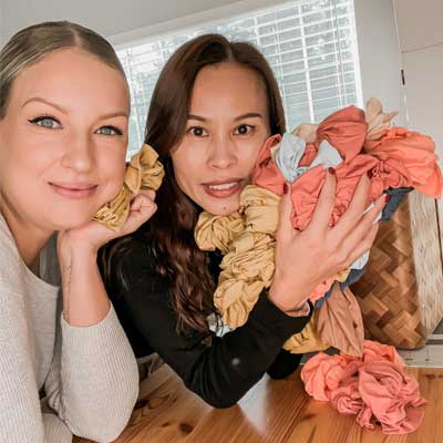 Two women posing with a bunch of scrunchies from Tiny Knot Co.