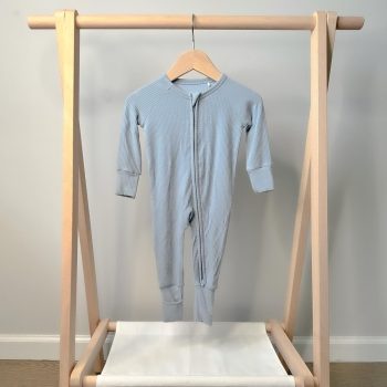 A baby's blue sleepsuit hanging on a wooden rack, from Tiny Knot Co.