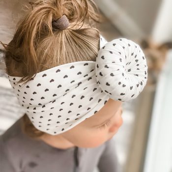 A baby wearing a Tiny Knot Co headband with a polka dot pattern.